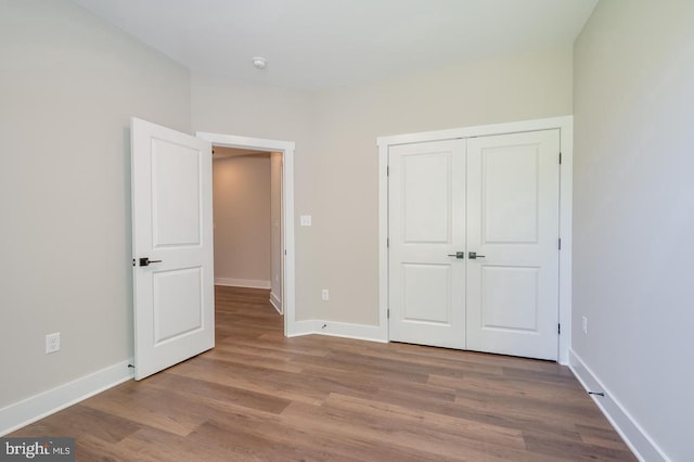 unfurnished bedroom featuring a closet, baseboards, and wood finished floors