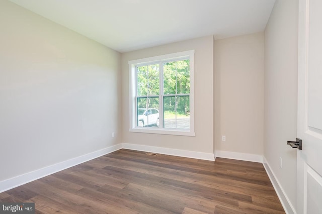 empty room featuring dark wood-type flooring and baseboards