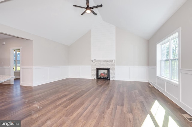 unfurnished living room featuring a brick fireplace, visible vents, vaulted ceiling, and wood finished floors