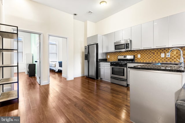 kitchen with stainless steel appliances, dark wood-type flooring, a sink, and backsplash