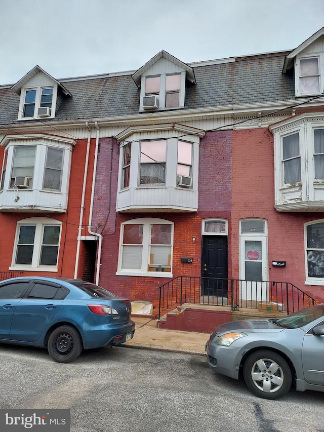 townhome / multi-family property featuring a shingled roof, cooling unit, and brick siding