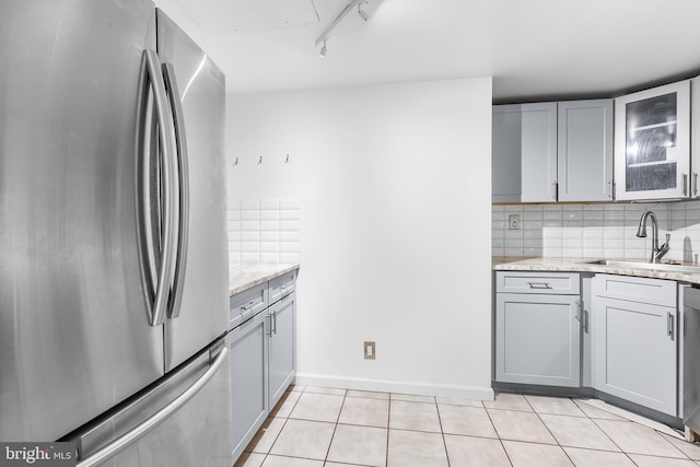 kitchen featuring appliances with stainless steel finishes, a sink, gray cabinetry, and light tile patterned floors