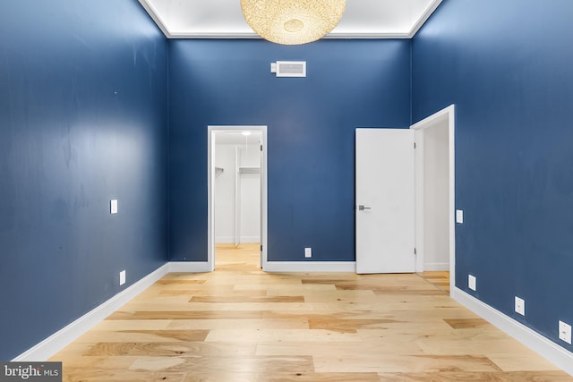 empty room featuring a towering ceiling, baseboards, visible vents, and wood finished floors