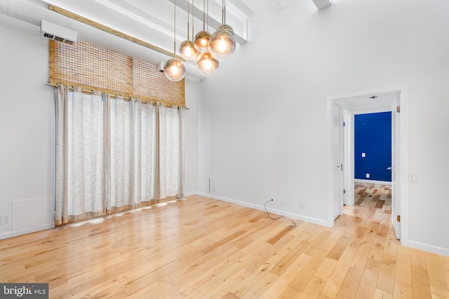 unfurnished dining area with a towering ceiling, hardwood / wood-style flooring, baseboards, and an inviting chandelier