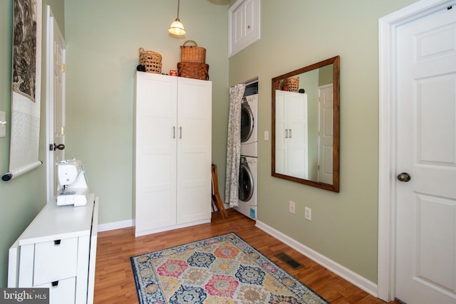 washroom with laundry area, visible vents, baseboards, stacked washer / dryer, and light wood-type flooring