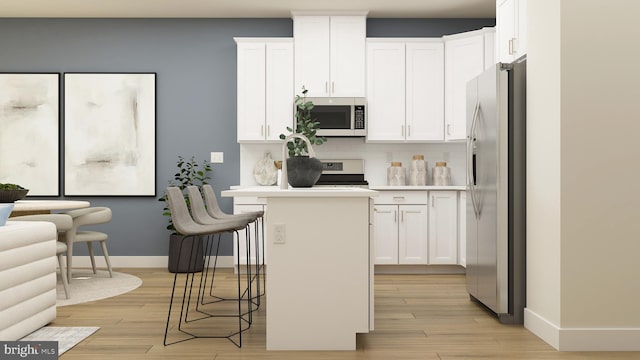 kitchen featuring stainless steel appliances, light countertops, white cabinetry, and a kitchen breakfast bar