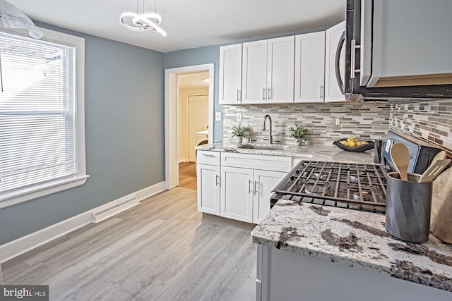 kitchen featuring a sink, visible vents, white cabinets, light stone countertops, and pendant lighting