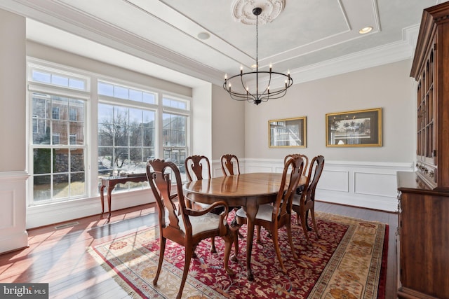 dining space featuring a tray ceiling, visible vents, ornamental molding, a chandelier, and hardwood / wood-style floors