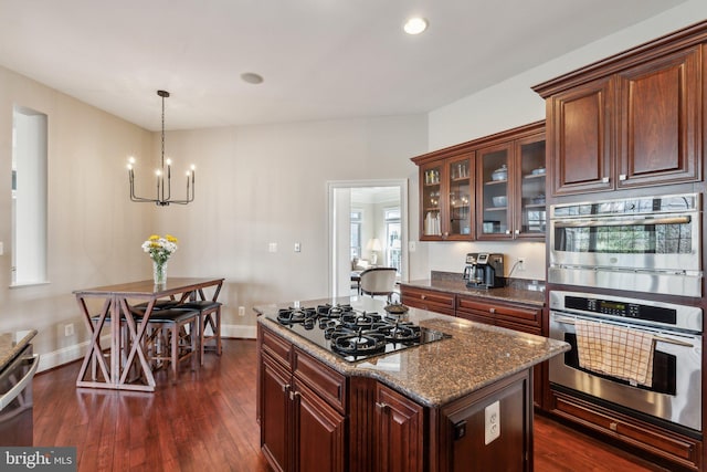 kitchen featuring black gas cooktop, double oven, glass insert cabinets, and dark wood finished floors