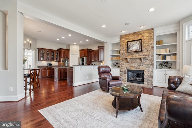 living room featuring dark wood-style floors, recessed lighting, a stone fireplace, and baseboards