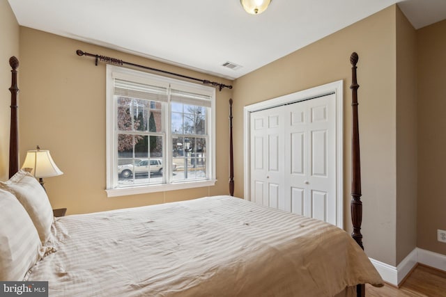 bedroom with baseboards, visible vents, a closet, and wood finished floors