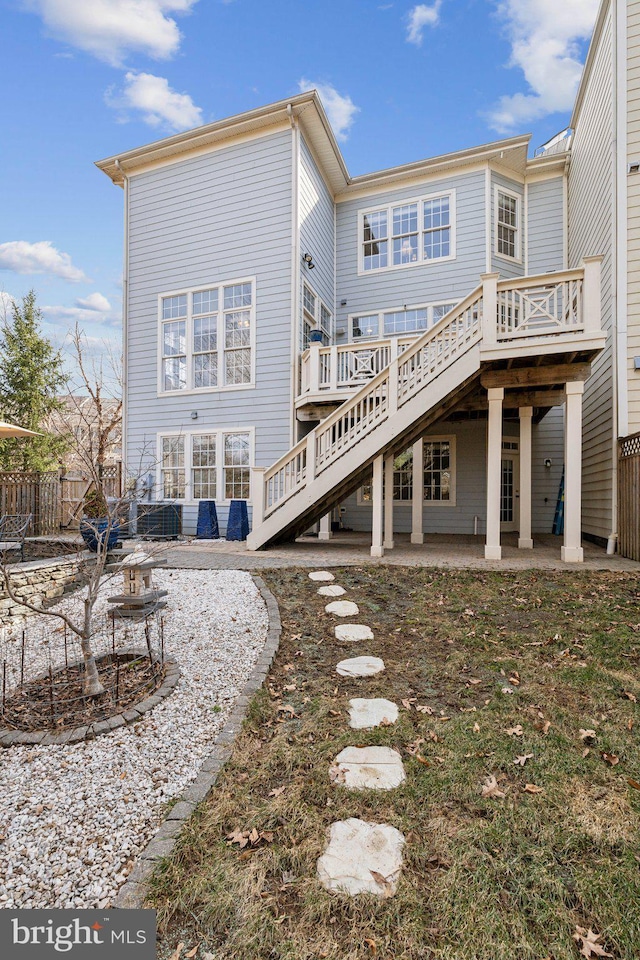 back of property with a deck, stairway, a patio area, and fence