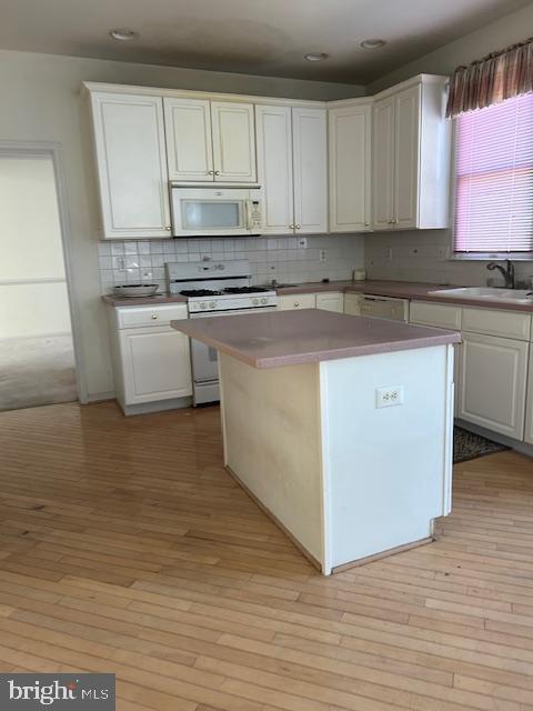 kitchen featuring white appliances, a sink, and white cabinetry