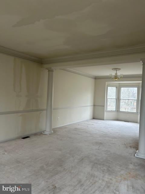 spare room featuring a notable chandelier, ornamental molding, visible vents, and ornate columns