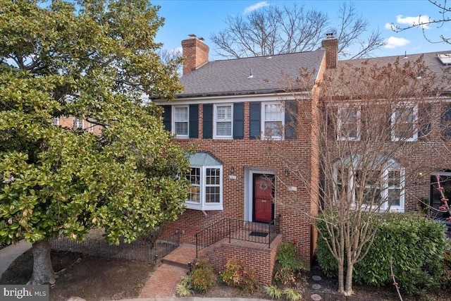 view of front of house with brick siding and a chimney