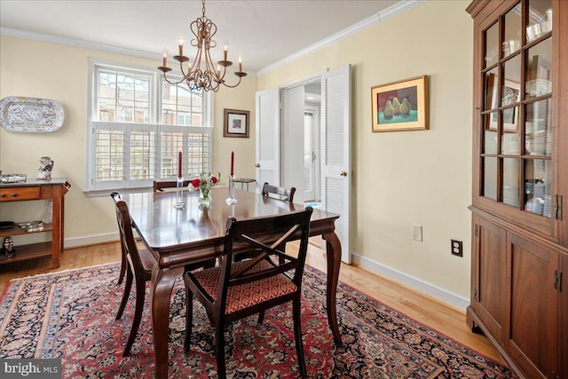 dining room featuring ornamental molding, light wood-style floors, baseboards, and an inviting chandelier