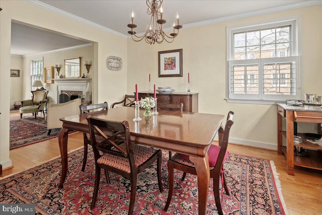 dining room with baseboards, light wood finished floors, a fireplace, and crown molding