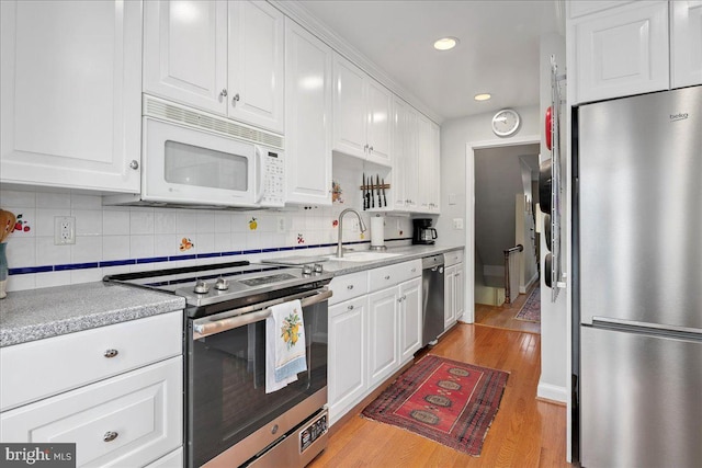 kitchen with light wood-type flooring, white cabinetry, appliances with stainless steel finishes, and a sink