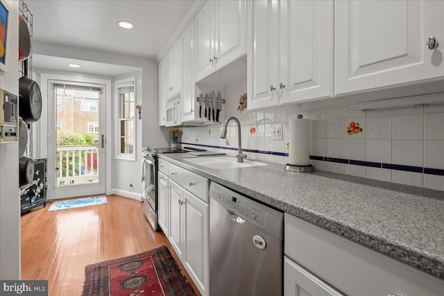 kitchen featuring stainless steel appliances, white cabinets, a sink, and light wood finished floors