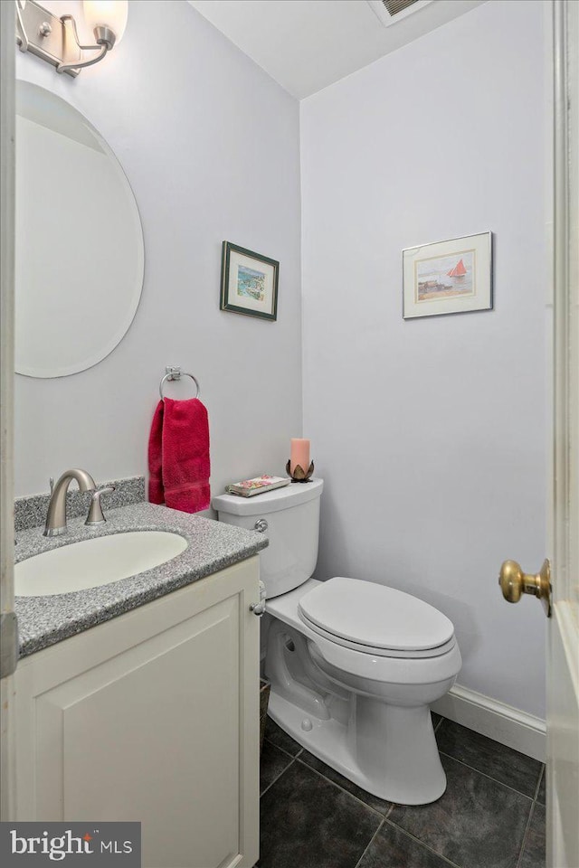 half bathroom with toilet, visible vents, baseboards, vanity, and tile patterned floors