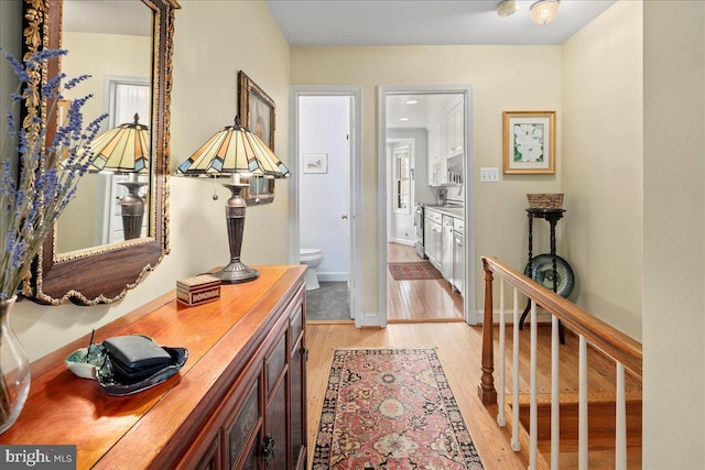 hall with baseboards and light wood finished floors