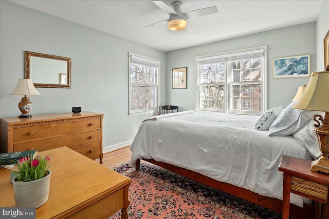 bedroom with light wood-style floors, ceiling fan, and baseboards