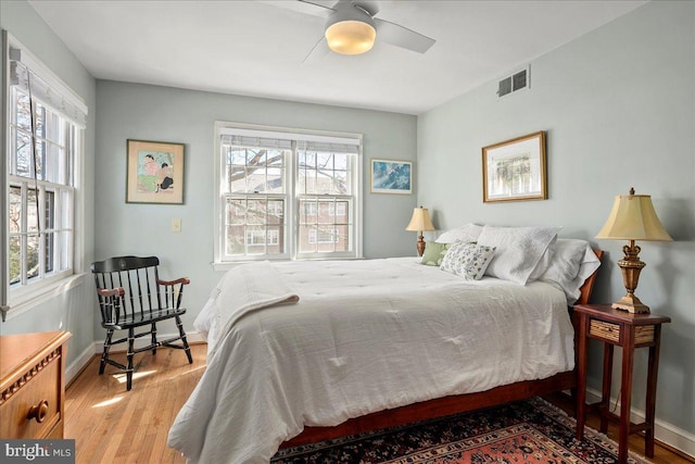 bedroom featuring baseboards, visible vents, ceiling fan, and wood finished floors