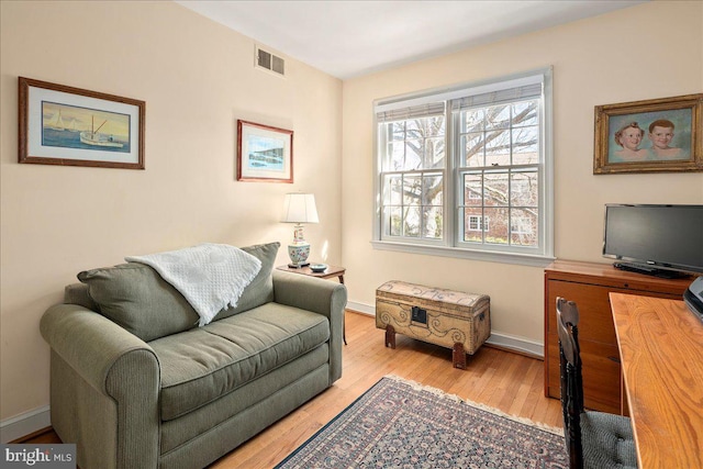 living area with wood finished floors, visible vents, and baseboards