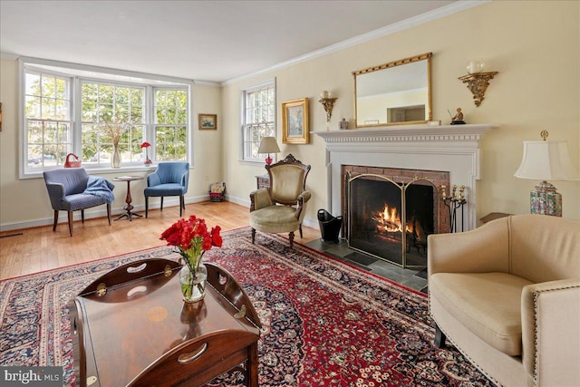 living area with a fireplace with flush hearth, crown molding, baseboards, and wood finished floors