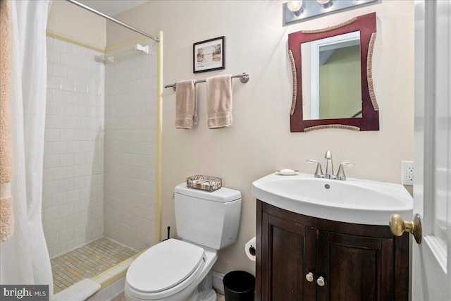 bathroom featuring a shower stall, toilet, and vanity