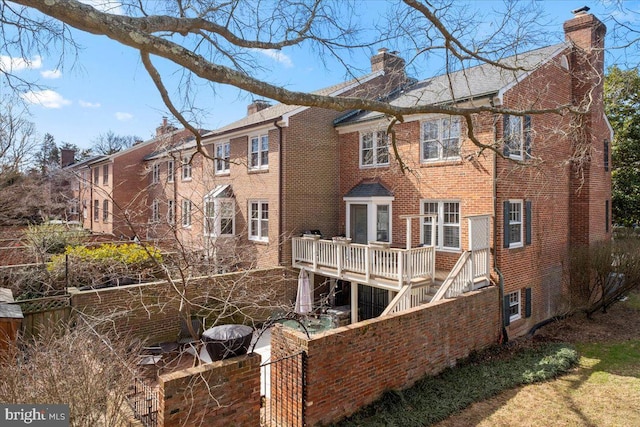 rear view of property with stairway, brick siding, fence, and a chimney