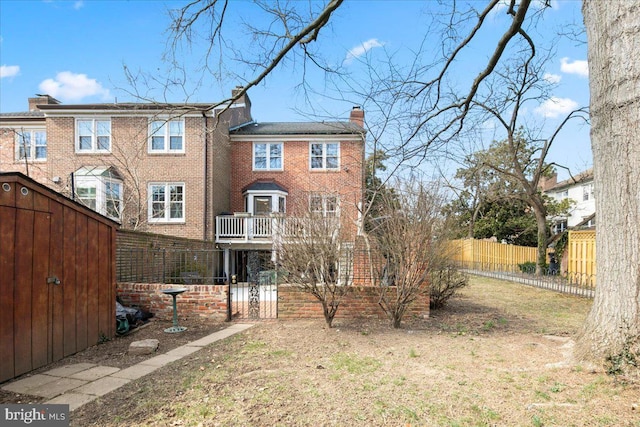 back of property with brick siding, a chimney, and fence private yard