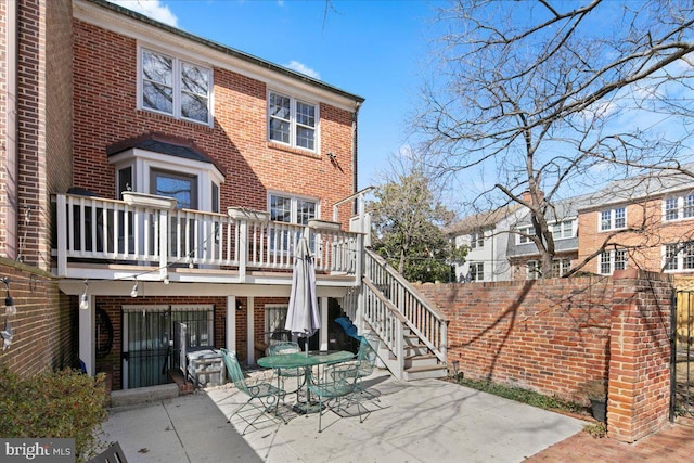 back of property featuring stairs, brick siding, and a patio area