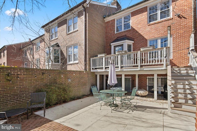 rear view of house featuring brick siding, stairway, a patio area, and outdoor dining area