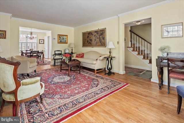 living room with ornamental molding, wood finished floors, a chandelier, and stairs