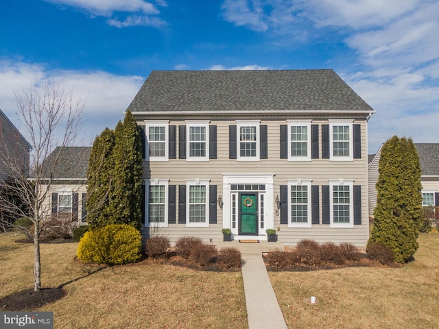 colonial-style house with a front lawn and roof with shingles