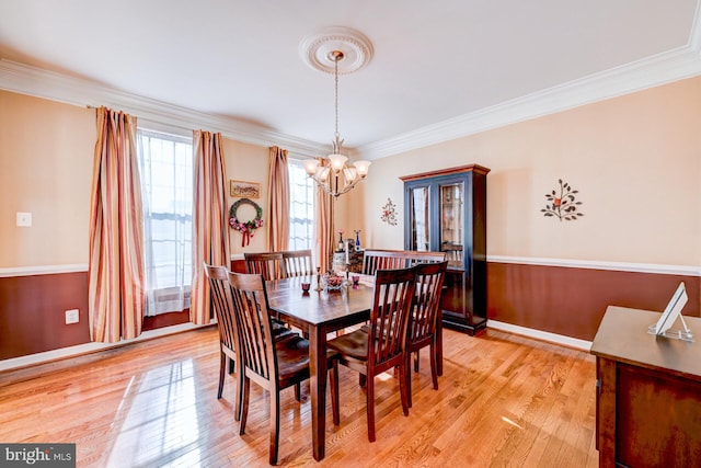 dining room with baseboards, ornamental molding, light wood-type flooring, and a notable chandelier