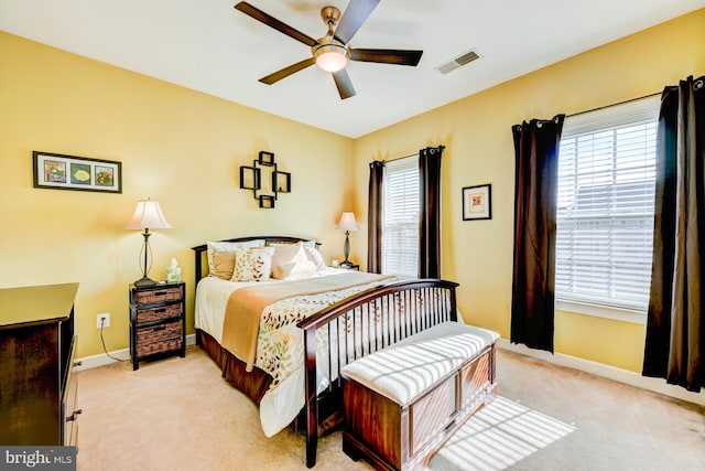 bedroom featuring baseboards, multiple windows, visible vents, and light colored carpet