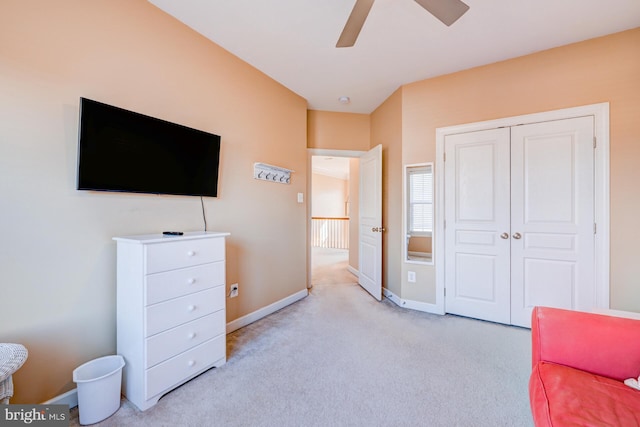 bedroom featuring light carpet, ceiling fan, a closet, and baseboards