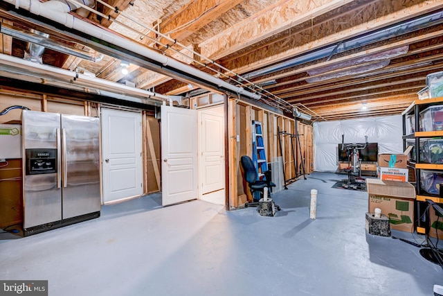 unfinished below grade area featuring stainless steel fridge with ice dispenser