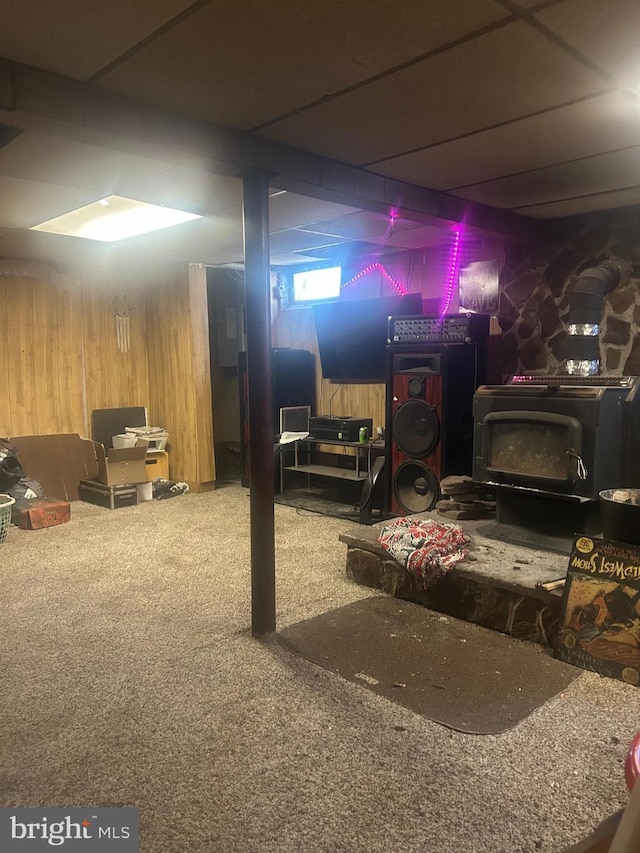 finished basement with a wood stove, wood walls, and carpet