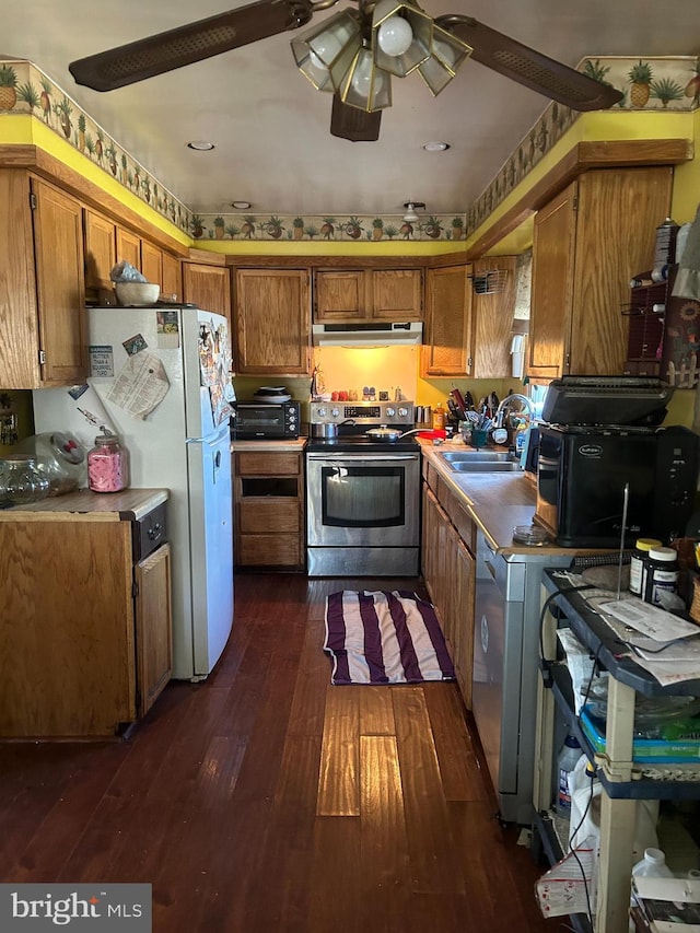 kitchen with under cabinet range hood, a sink, brown cabinetry, dark wood finished floors, and stainless steel range with electric stovetop