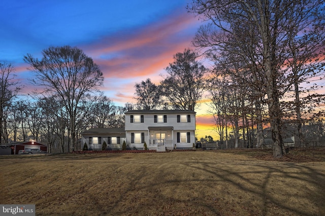 view of front of property featuring a yard, covered porch, and a chimney