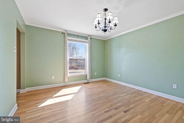 spare room with a chandelier, baseboards, crown molding, and light wood-style floors