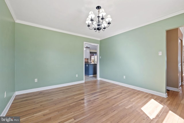 empty room featuring a notable chandelier, baseboards, and light wood-type flooring