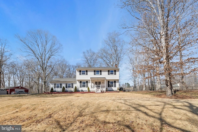 colonial home with a front yard, covered porch, and a chimney