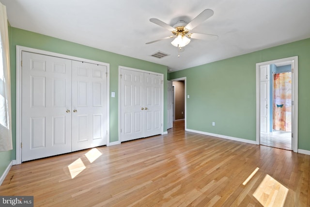 unfurnished bedroom with visible vents, baseboards, multiple closets, light wood-style flooring, and a ceiling fan