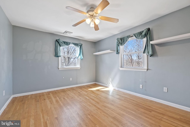 spare room with wood finished floors, visible vents, a wealth of natural light, and baseboards