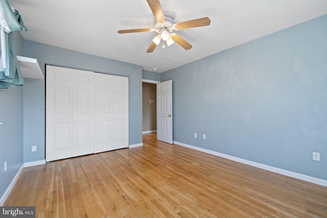 unfurnished bedroom with light wood finished floors, a closet, baseboards, and a ceiling fan