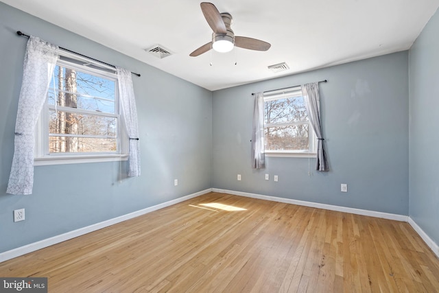 spare room featuring baseboards, visible vents, wood-type flooring, and ceiling fan